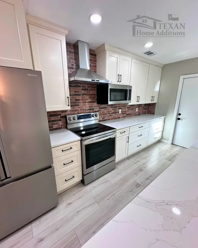 Texan Home Additions kitchen remodel with cream shaker cabinets, red-brick backsplash, stainless hood, and electric range